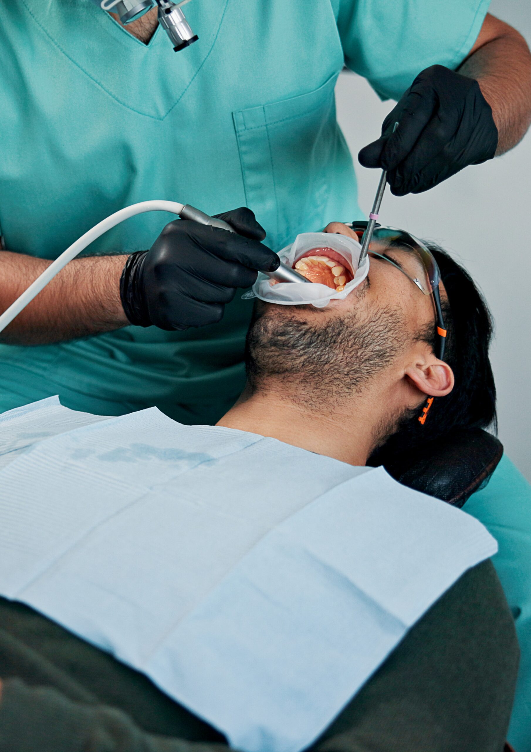 Man, patient and dentist cleaning mouth with tools for bacteria or germ removal at orthodontist. Male person, client or teeth surgeon with suction for tooth extraction, dental or oral care at clinic