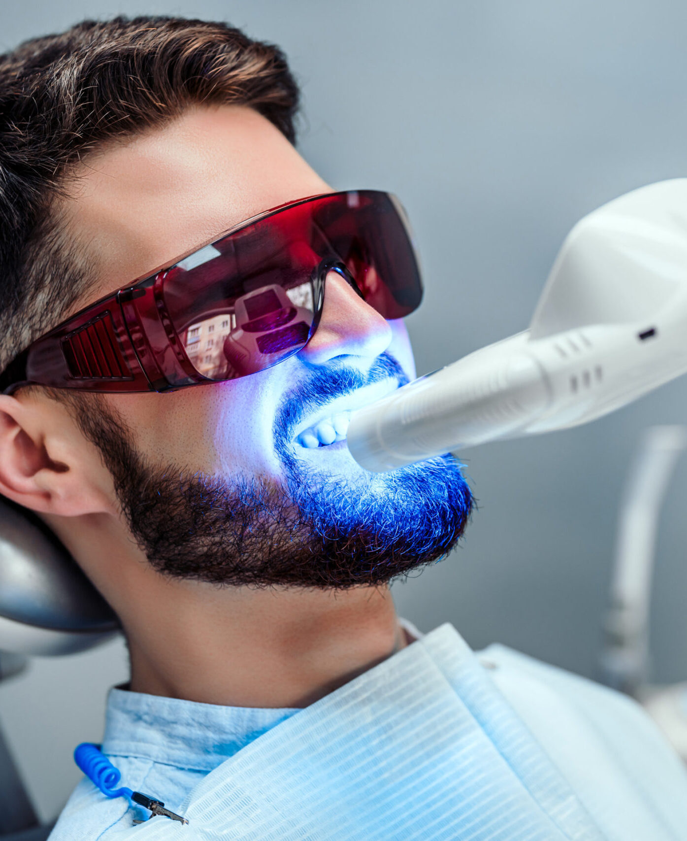 Close up view of man undergoing laser tooth whitening treatment to remove stains and discoloration.