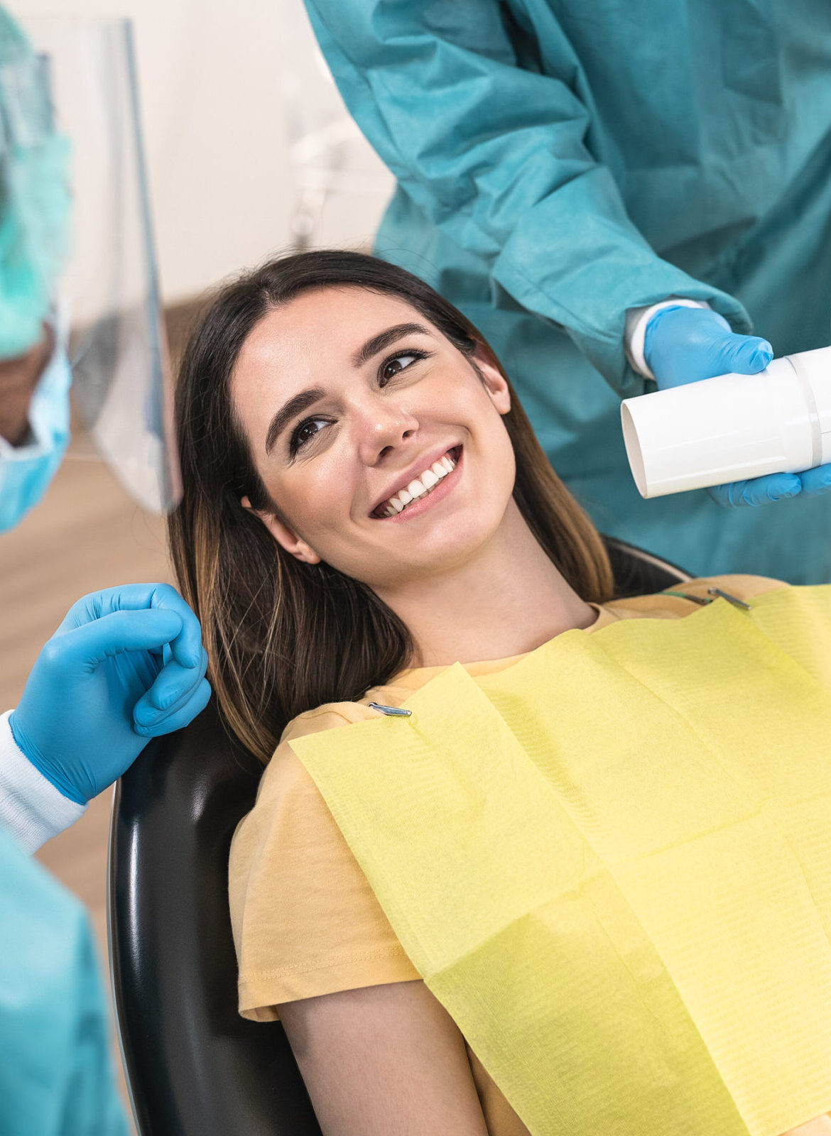 Man dentist operating young smiling woman in dental clinic - Oral heathcare assistance concept