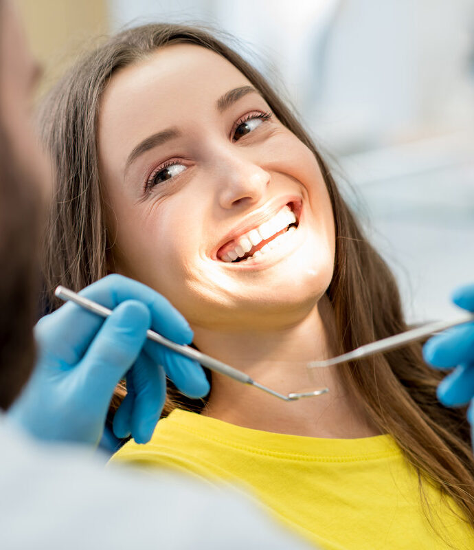 Portrait of a woman with toothy smile sitting during examination at the dental office